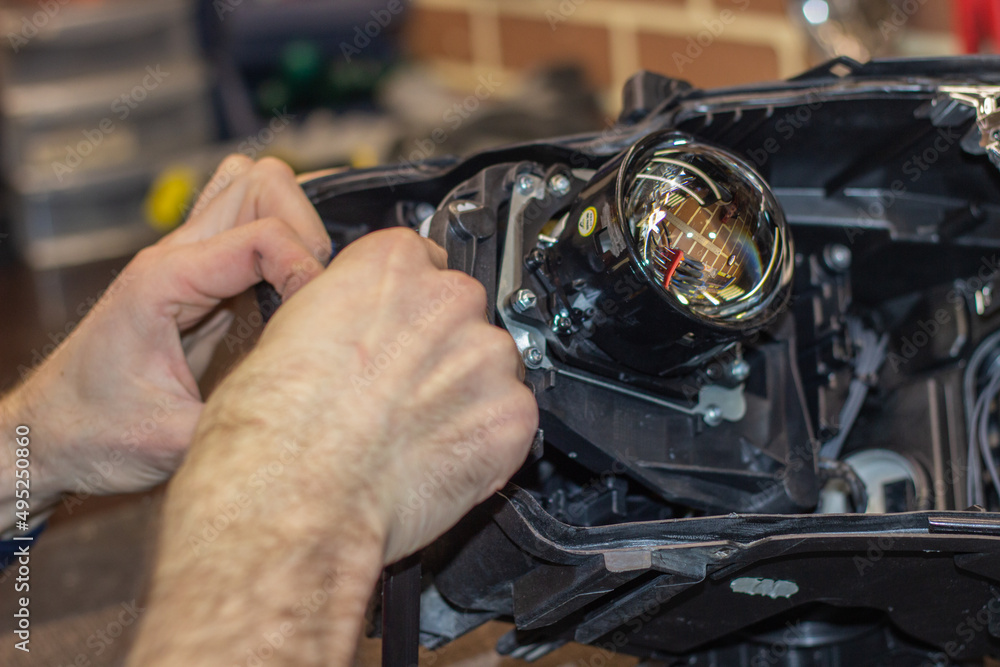 Car headlight in repair closeup. The car mechanic installs the lens in