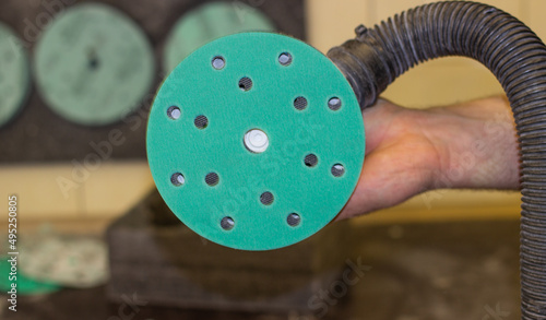 A person changes green sandpaper for a sander.  The master changes the emery wheel on the grinder.  An abrasive disc for an orbital grinder.