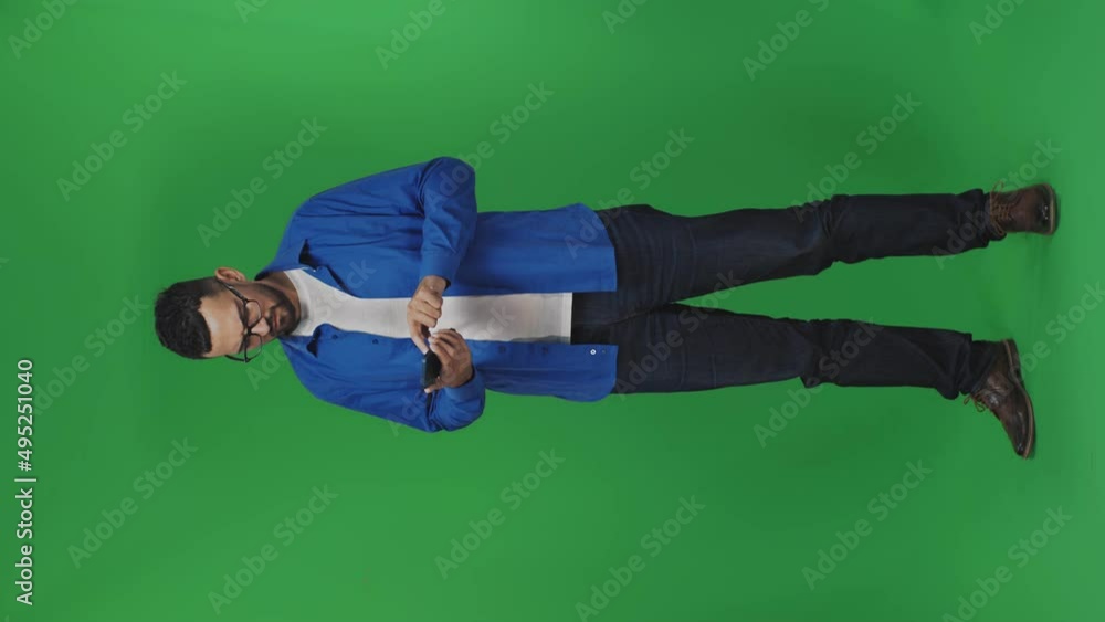 A young man scrolling on his smartphone. Green screen background. Vertical video A young man scrolling on his smartphone. Green screen background. Vertical video