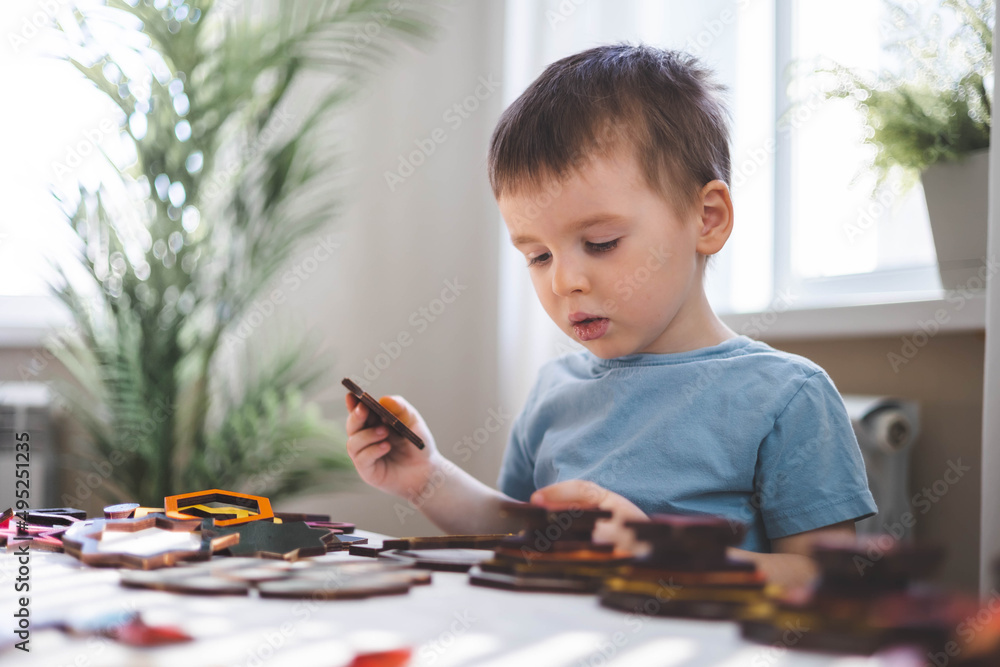 Attentive cute baby boy learning geometric figure shapes playing multicolored wooden construction Attentive cute baby boy learning geometric figure shapes playing multicolored wooden construction