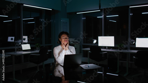 African-American businesswoman work late in dark office and suffer from neck ache