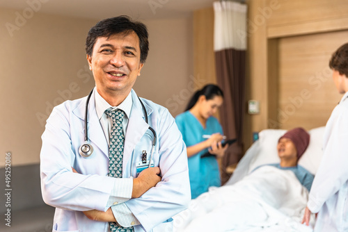 Young Asian elder man in medical robe smiling and looking at camera during work against at clinic.. healthcare medical checkup concept.