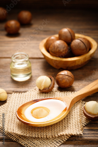 Macadamia oil and Macadamia nuts on a wooden background. Natural vitamins.