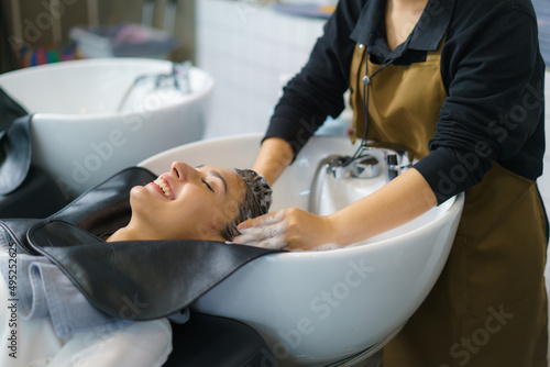 hairdresser is applying shampoo and massaging hair of a customer. Woman having her hair washed in a hairdressing salon..