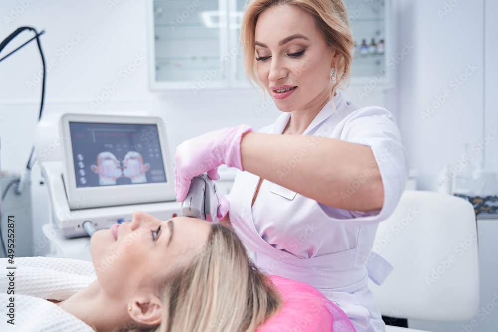 Cosmetician performing skin tightening procedure on customer Cosmetician performing skin tightening procedure on customer