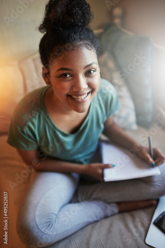 Studying with a smile. High angle portrait of a young female student studying at home.