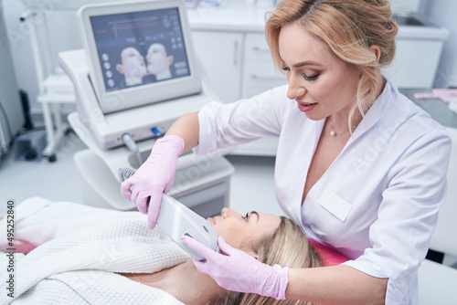 Focused dermatologist conducting ultrasound procedure on client