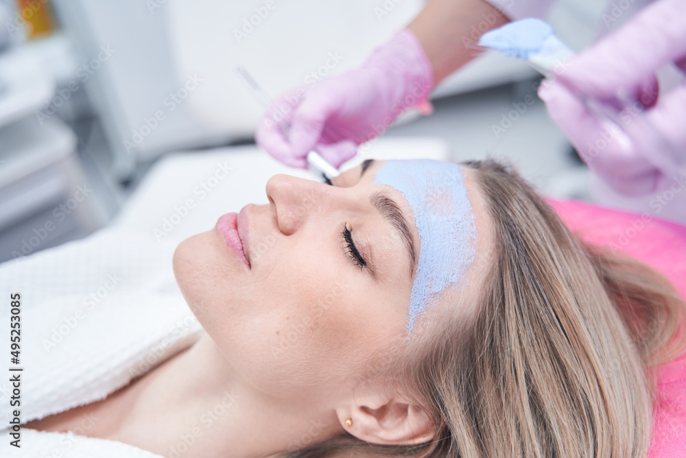 Fototapeta premium Calm spa client dozing during blue clay mask application