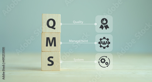 QMS, Quality management system concept. Formalized system for achieving quality policies and objectives.  ISO 9001 standard.  Wooden cubes with abbreviation of QMS and symbols on smart background. photo