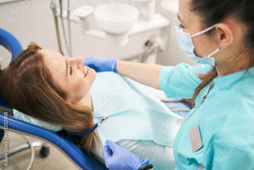 Doctor preparing woman for dental procedure in clinic