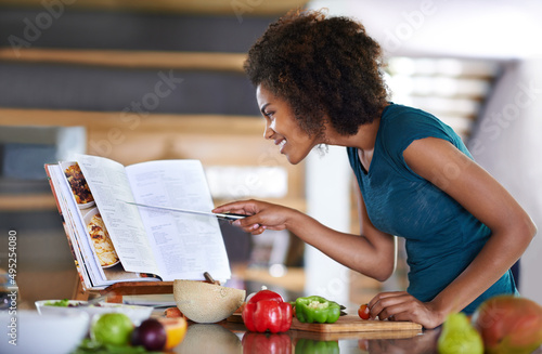 Following the recipe to the letter. A young woman cooking from a recipe book. photo