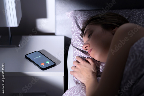 Fototapeta Phone call by unknown caller at night while woman is sleeping in bed