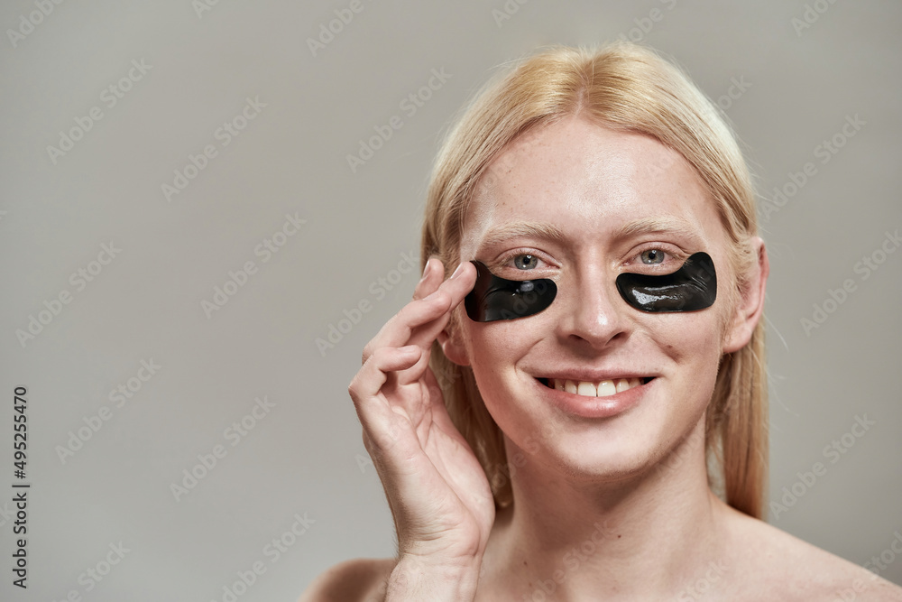 Caucasian guy applying under eye patch on face Caucasian guy applying under eye patch on face