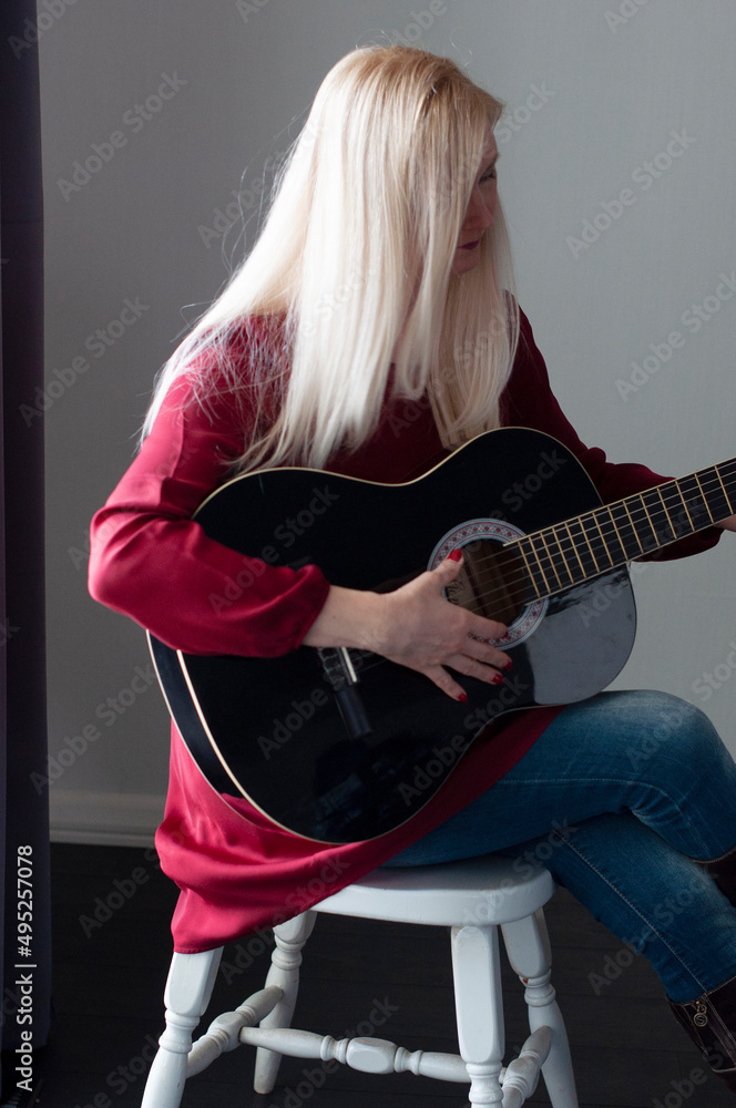 beautiful young blonde woman in a red dress with a black guitar, favorite hobby beautiful young blonde woman in a red dress with a black guitar, favorite hobby