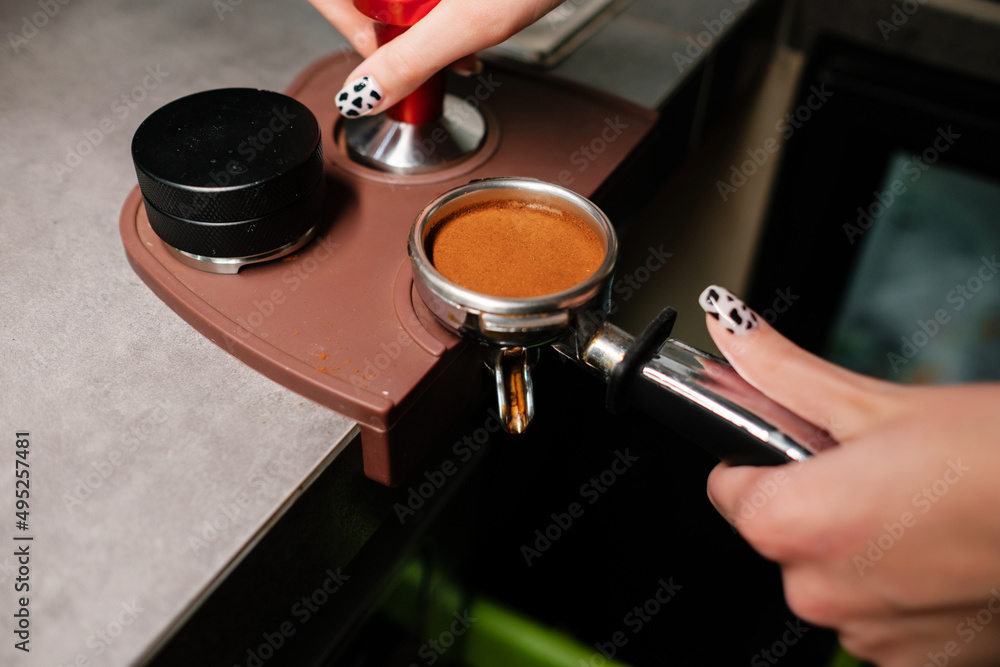 Barista prepares cappuccino using a coffee machine. Coffee tamping process.