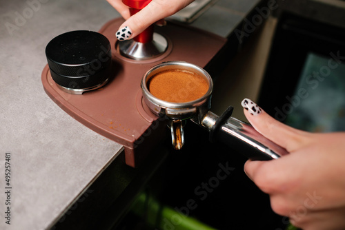 Barista prepares cappuccino using a coffee machine. Coffee tamping process.