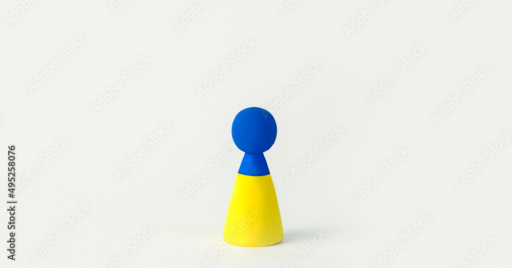 Ukraine flag concept. A wooden man with a symbol of the Ukrainian flag stands on a white background. Banner. copy space. Ukraine flag concept. A wooden man with a symbol of the Ukrainian flag stands on a white background. Banner. copy space.
