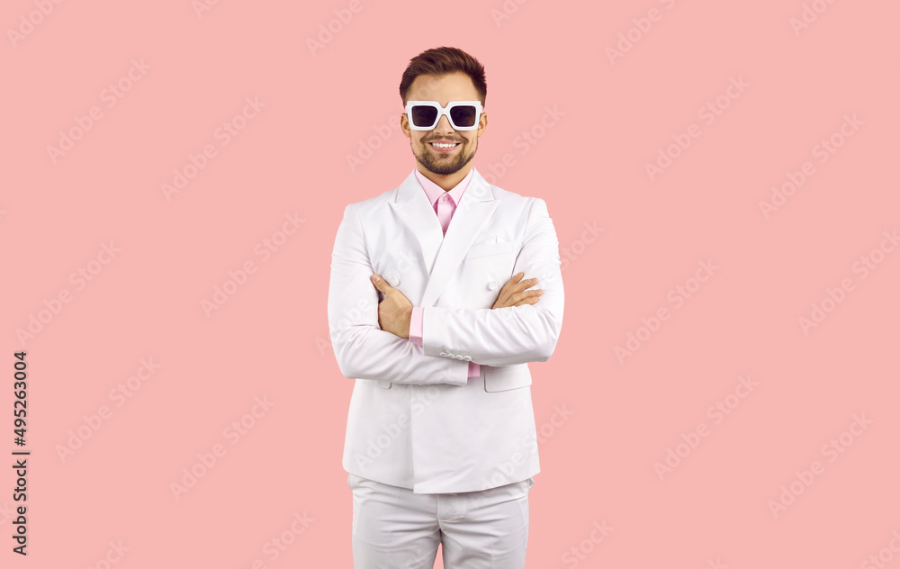 Portrait of happy young Caucasian man in suit and glasses stand pose isolated on pink studio background. Smiling millennial guy performer or entertainer in formal costume and spectacles.