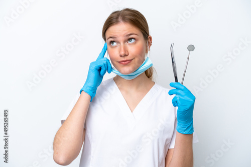 Dentist caucasian woman holding tools isolated on white background having doubts and thinking