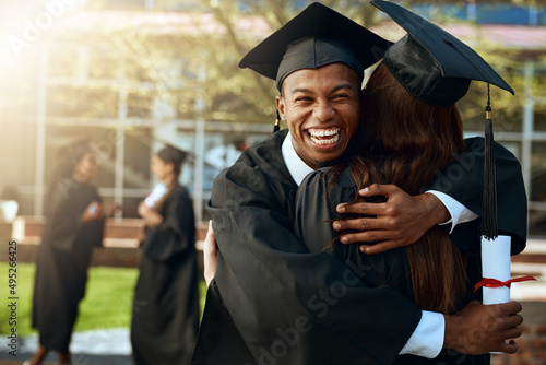 Together forever in love and education. Portrait of a happy young man and woman hugging on graduation day. photo