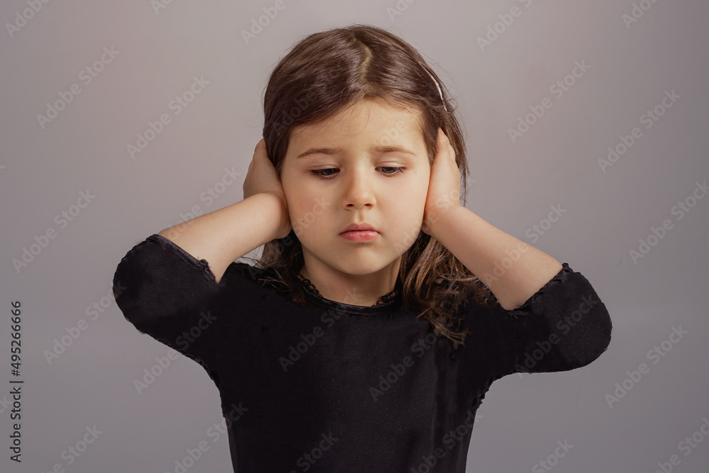 The little girl covered her ears with her hands and does not want to listen to anyone. Portrait of a naughty child 4 years old The little girl covered her ears with her hands and does not want to listen to anyone. Portrait of a naughty child 4 years old