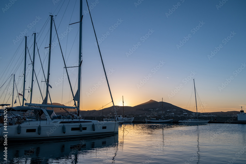Sunset over Paros Greek island, Cyclades. Yacht and boat moored at port dock blue sky background.