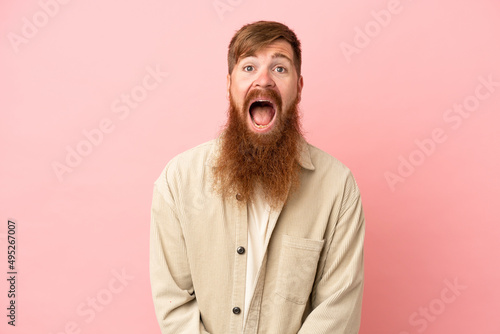 Young reddish caucasian man isolated on pink background with surprise facial expression © luismolinero