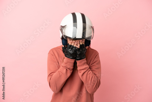 Young reddish caucasian man with a motorcycle helmet isolated on pink background with tired and sick expression