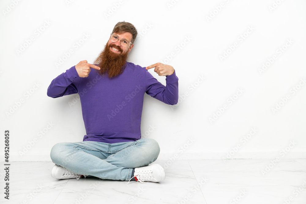 Young caucasian reddish man sitting on the floor isolated on white background proud and self-satisfied
