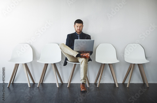 Keeping me busy waiting. Studio shot of a businessman waiting in line against a white background.