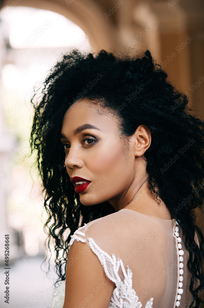 Beautiful african american woman posing at camera in white dress. Portrait of cheerful young woman with afro hairstyle. Beauty girl with curly hair. Beautiful african american woman posing at camera in white dress. Portrait of cheerful young woman with afro hairstyle. Beauty girl with curly hair.