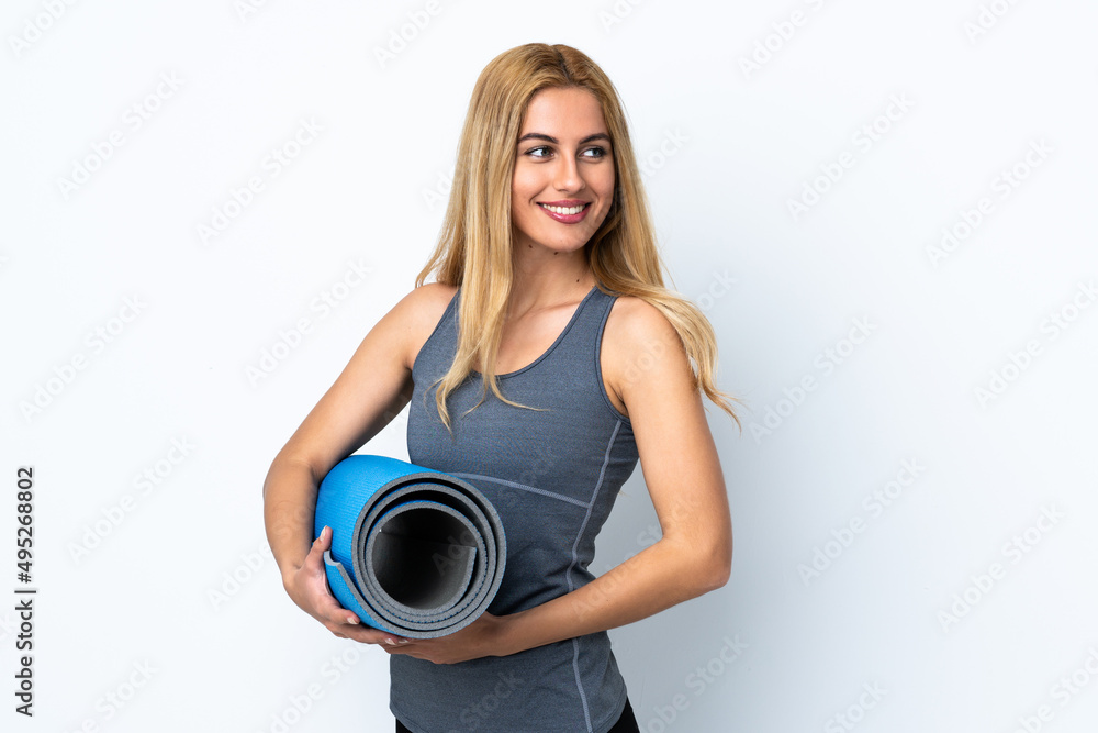 Young sport woman going to yoga classes while holding a mat over isolated white background Young sport woman going to yoga classes while holding a mat over isolated white background