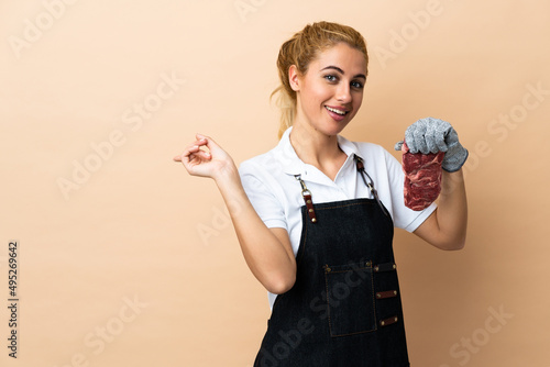 Butcher woman wearing an apron and serving fresh cut meat over isolated background pointing finger to the side photo