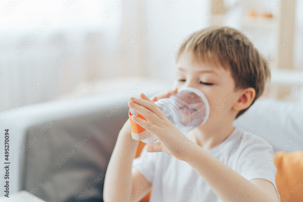 Little boy inhales medicine through homemade spacer.