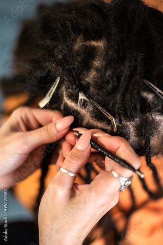 braiding dreadlocks by a master hairdresser. close-up