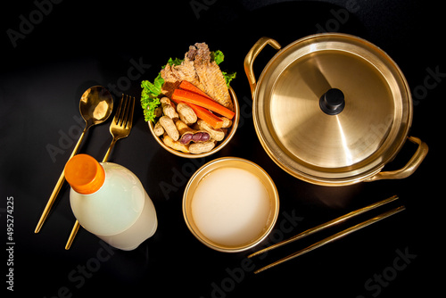 Makgeolli rice wine is a Korean fermented alcoholic beverage traditional drinks. 
Korean alcoholic drink (Makgeolli) in a traditional Korean gold liquor bowl with snack on Black background.  photo