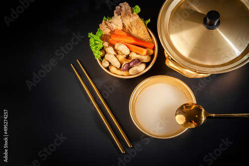 Makgeolli rice wine is a Korean fermented alcoholic beverage traditional drinks. 
Korean alcoholic drink (Makgeolli) in a traditional Korean gold liquor bowl with snack on Black background.  photo