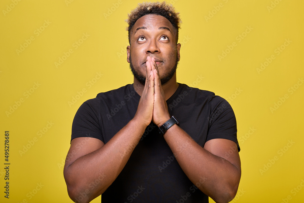 A black man athletic begs God to fulfill his long-held dream. A rather agitated modern African-American holds his hands with his palms together, prays for good luck, dreams of winning. A black man athletic begs God to fulfill his long-held dream. A rather agitated modern African-American holds his hands with his palms together, prays for good luck, dreams of winning.