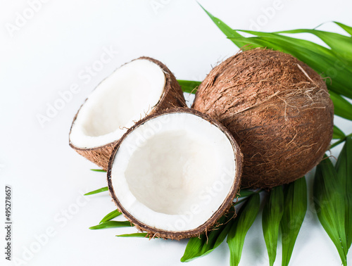 Ripe half cut coconut with green leaves on a white background. Isolated concept.