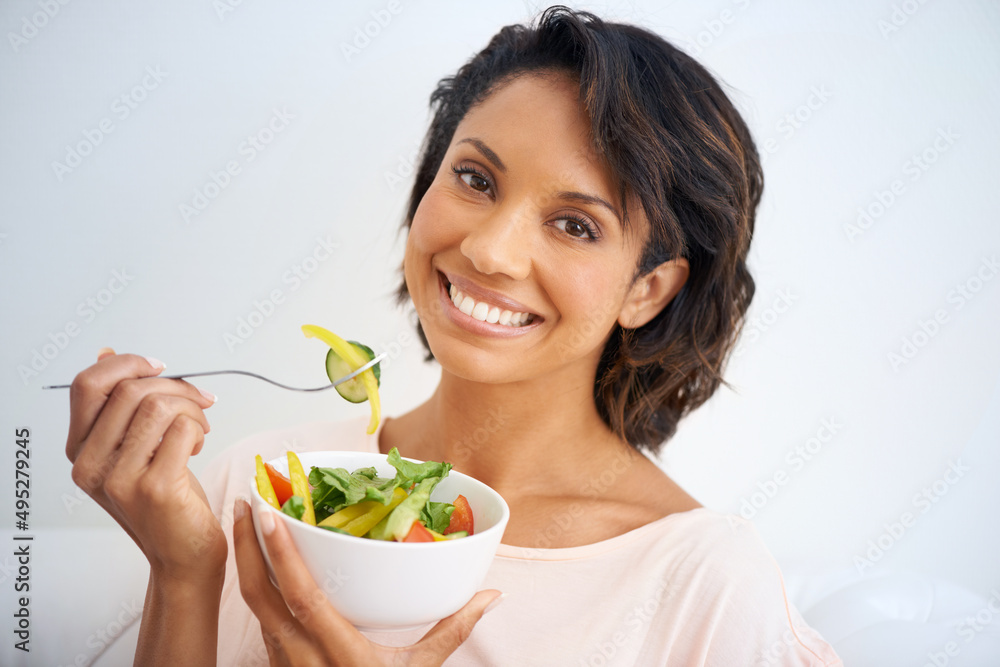 Feeling good starts with eating right. Portrait of a young woman enjoying a salad at home. Feeling good starts with eating right. Portrait of a young woman enjoying a salad at home.