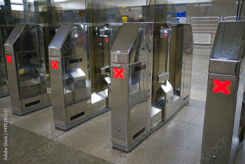 Automatic turnstiles with a burning red crosshair. The passage is closed at the turnstiles of the metro. Silver turnstile stands. Red alarm system in the subway.