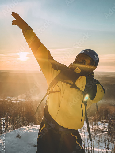 Snowboarder posing on top of a mountain at sunset