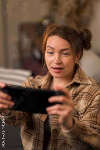 A girl plays a mobile game on a portable game console. He looks at the screen in surprise. Close-up. Video games, online games with friends, fun, prizes, wins, youth culture, game strategy.