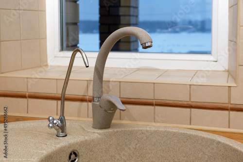 Kitchen faucet. Artificial stone sink with two taps, plain and filtered water. Fragment of modern kitchen. Filter system or osmosis, water purification. photo