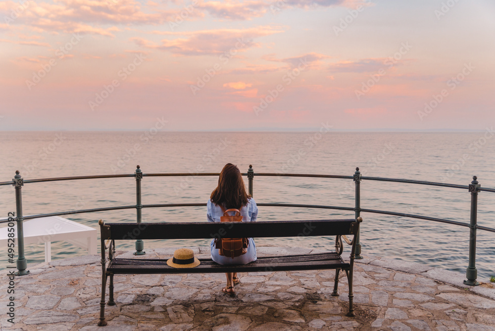 woman sitting on bench and looking at the sea
