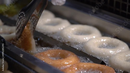 Frying homemade donuts in hot boiling oil, cooking greasy food. donuts