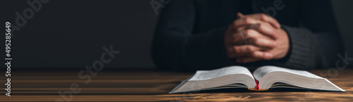 Hands of praying young man and Bible