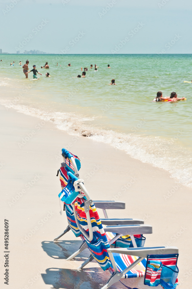 Obraz premium side view, medium distance of, two colorful, beach chairs, on the edge of a tropical shoreline, on a sunny afternoon