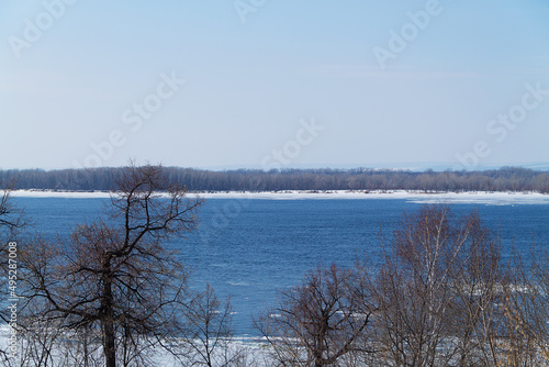 trees on the river. landscape of winter forest with sunlight and snow. blue river with ice and snow.