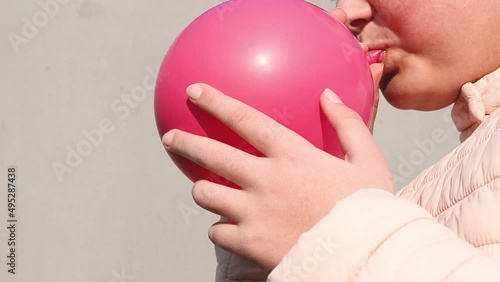 Close-up girl inflating pink balloon outdoors,video 4k